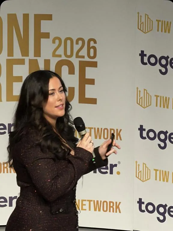 Emma speaking on stage with a microphone at a property conference