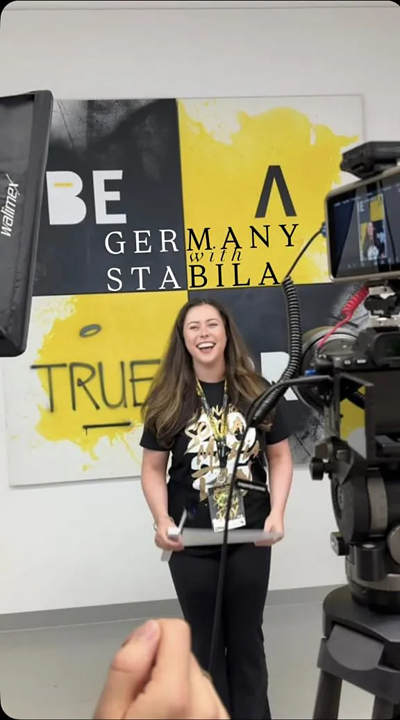 Emma laughing in front of a camera at STABILA headquarters